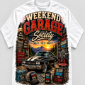 A white short-sleeve crewneck t-shirt featuring a large graphic print on the front. The graphic is themed 'Weekend Garage Society' and displays a black muscle car, a workbench, tools, a hat, a mug, and a stool, all in a rustic garage setting with a sunset sky background.