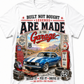 A white short-sleeve crewneck t-shirt featuring a large, detailed vintage-style graphic print on the front. The graphic depicts a blue muscle car with white stripes, a red vintage gas pump, a red tool chest, a helmet, and desert scenery under a sunset sky, with bold text reading 'BUILT NOT BOUGHT LEGENDS ARE MADE IN THE Garage'.