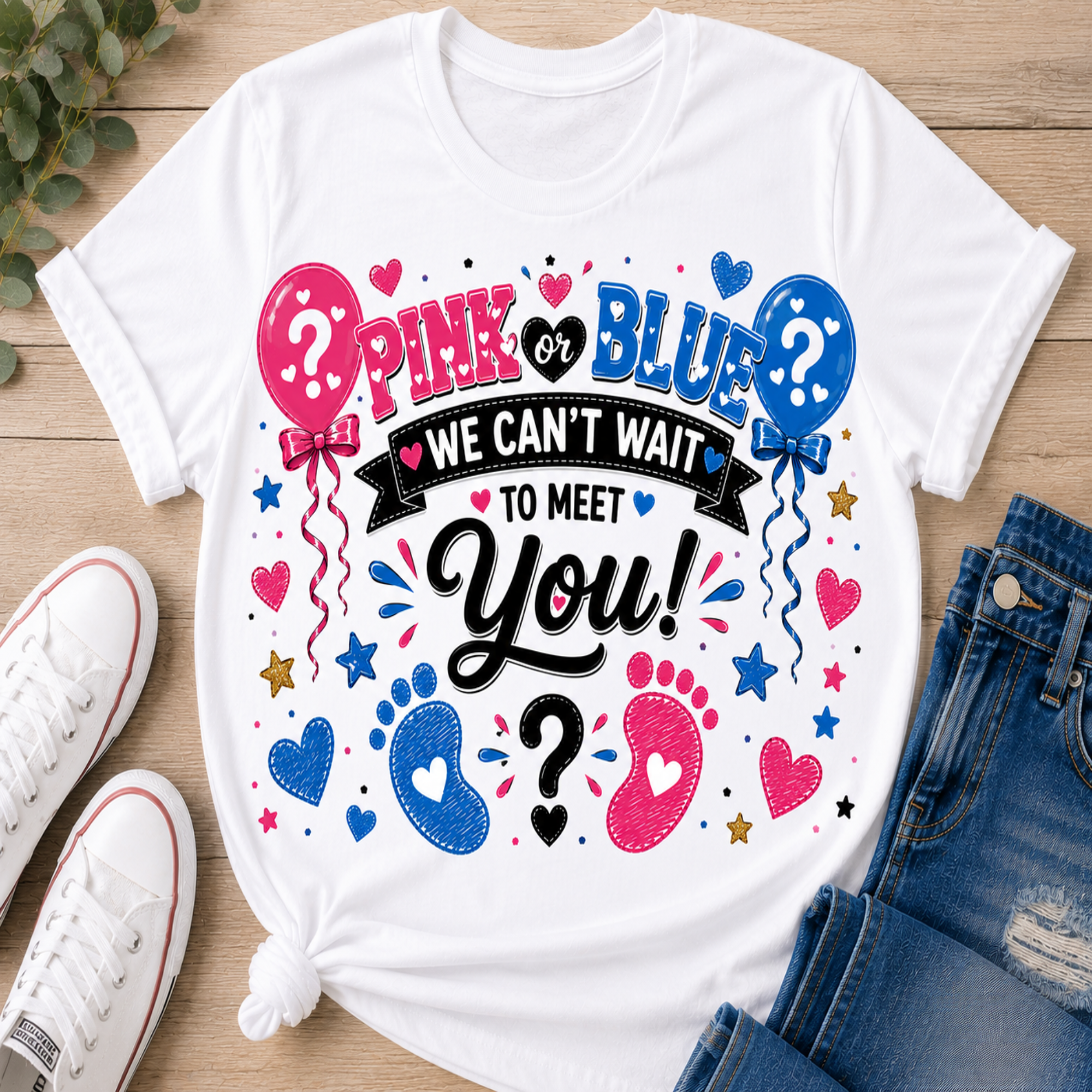 A white graphic t-shirt laid flat on a wooden surface, styled with white sneakers and blue jeans. The shirt features a colorful design with pink and blue balloons, hearts, stars, and baby footprints around the text 'PINK or BLUE WE CAN'T WAIT TO MEET You!'.