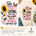 A graphic design print featuring a motivational quote about starting to live, shown on a cream t-shirt mockup and as a standalone digital design. The design includes a large sunflower, butterflies, hearts, and the quote 'She decided to start living the life she imagined and the world opened up' in black, pink, and white text.