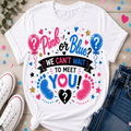 A white graphic t-shirt featuring a colorful 'Pink or Blue' baby shower design, styled in a flat-lay arrangement with white sneakers, blue jeans, and confetti on a light wood background.