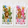 Two white short-sleeve baby t-shirts shown side by side, each printed with a colorful cartoon bear and lion birthday design that reads '4 ROAR I'm Four' with balloons, flowers, stars, and a crown.