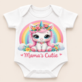 A white short-sleeve baby bodysuit with a colorful cartoon unicorn graphic and the text 'Mama's Cutie' printed on the front, shown against a light beige background.