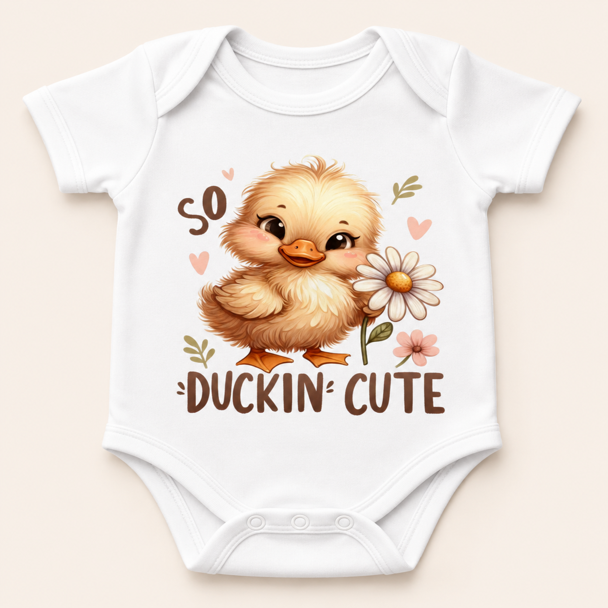A white short-sleeve baby bodysuit with a cute cartoon duckling graphic holding a daisy, surrounded by the words 'so DUCKIN' CUTE' on a light beige background.