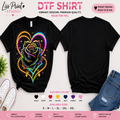 A product mockup showing two views of a black DTF (Direct to Film) t-shirt. The left view shows a vibrant, colorful graphic of a glowing rainbow heart and rose.