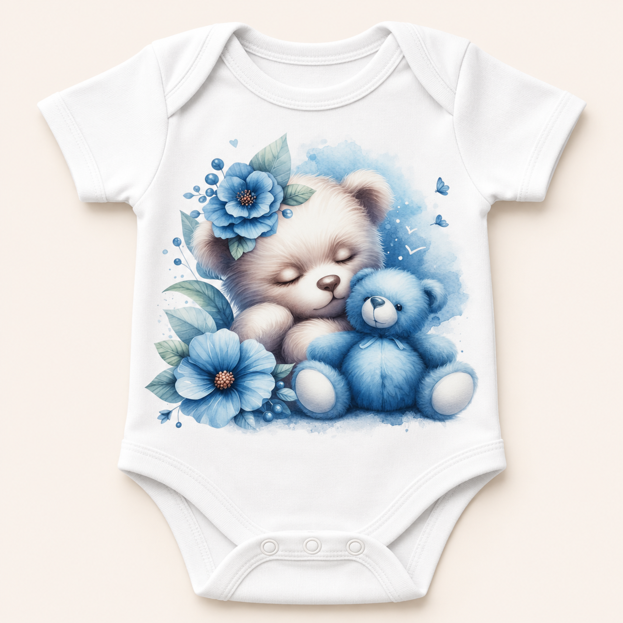 White short-sleeve baby bodysuit with a watercolor-style graphic of a sleeping beige teddy bear hugging a blue teddy bear, surrounded by blue flowers and leaves, shown on a light beige background.