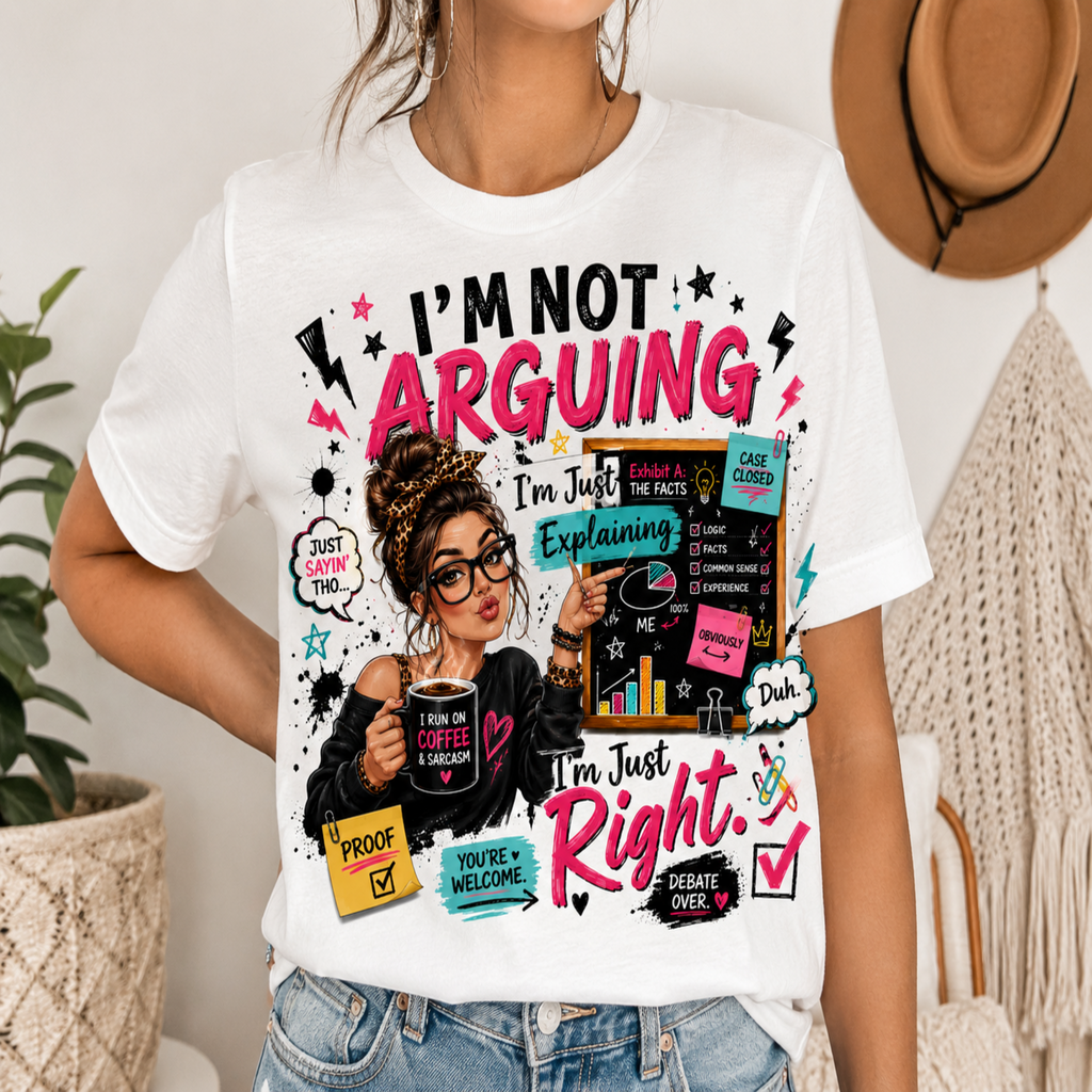 A woman wearing a white graphic t-shirt with a colorful design that reads 'I'M NOT ARGUING I'm Just Explaining I'm Just Right.' She is also wearing blue jeans, and the background shows a cozy indoor setting with a woven chair, a hat, and a plant.
