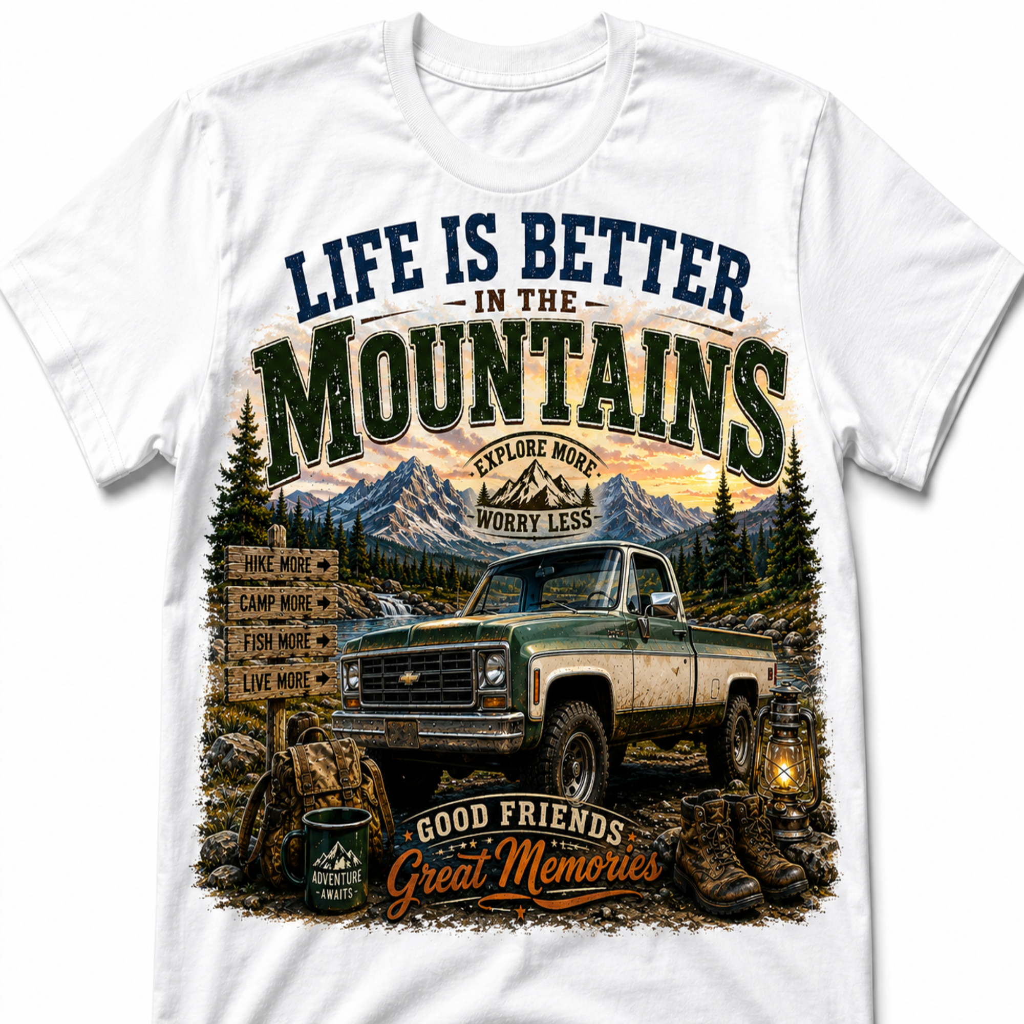 A white short-sleeve crewneck t-shirt featuring a large graphic print on the front. The graphic depicts a vintage green pickup truck in a mountain landscape with pine trees, a campsite signpost, and text reading 'LIFE IS BETTER IN THE MOUNTAINS' and 'GOOD FRIENDS Great Memories'.