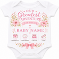 A white short-sleeve baby bodysuit with a pink and green floral graphic and text that reads 'Our Greatest Adventure Has Begun' and 'Baby Name,' plus baby milestone icons below.