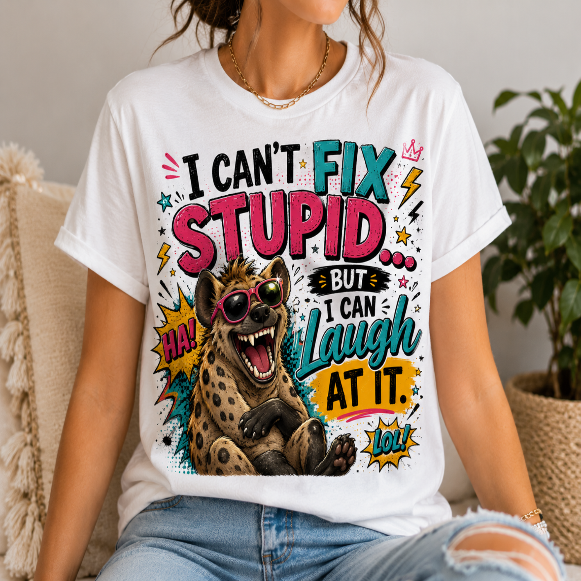 A woman wearing a white graphic t-shirt with a colorful print of a hyena wearing sunglasses and the text 'I CAN'T FIX STUPID.