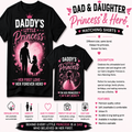 A promotional graphic for matching dad and daughter t-shirts. It shows two black short-sleeve t-shirts with pink and white printed designs: one large front view and one smaller back view.