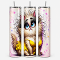 Three views of a tall insulated tumbler with a clear lid and straw, printed with a whimsical cartoon cat illustration in beige, brown, yellow, pink, and purple on a light background.