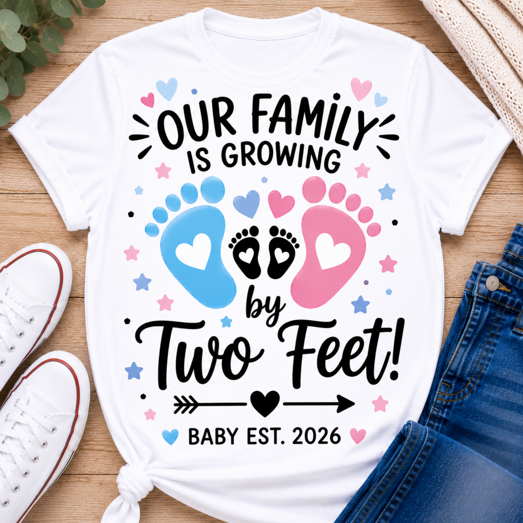 A white graphic T-shirt laid flat on a wood surface with white sneakers, a knit sweater, and blue jeans around it. The shirt reads “OUR FAMILY IS GROWING by Two Feet! BABY EST.