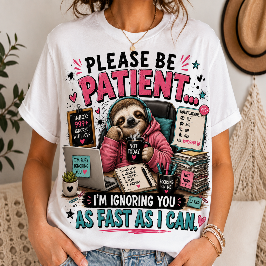 A woman wearing a white graphic t-shirt with a humorous sloth 'patient mode' design. The shirt features a cartoon sloth in a pink hoodie ignoring a laptop and stack of papers, surrounded by text like 'PLEASE BE PATIENT.