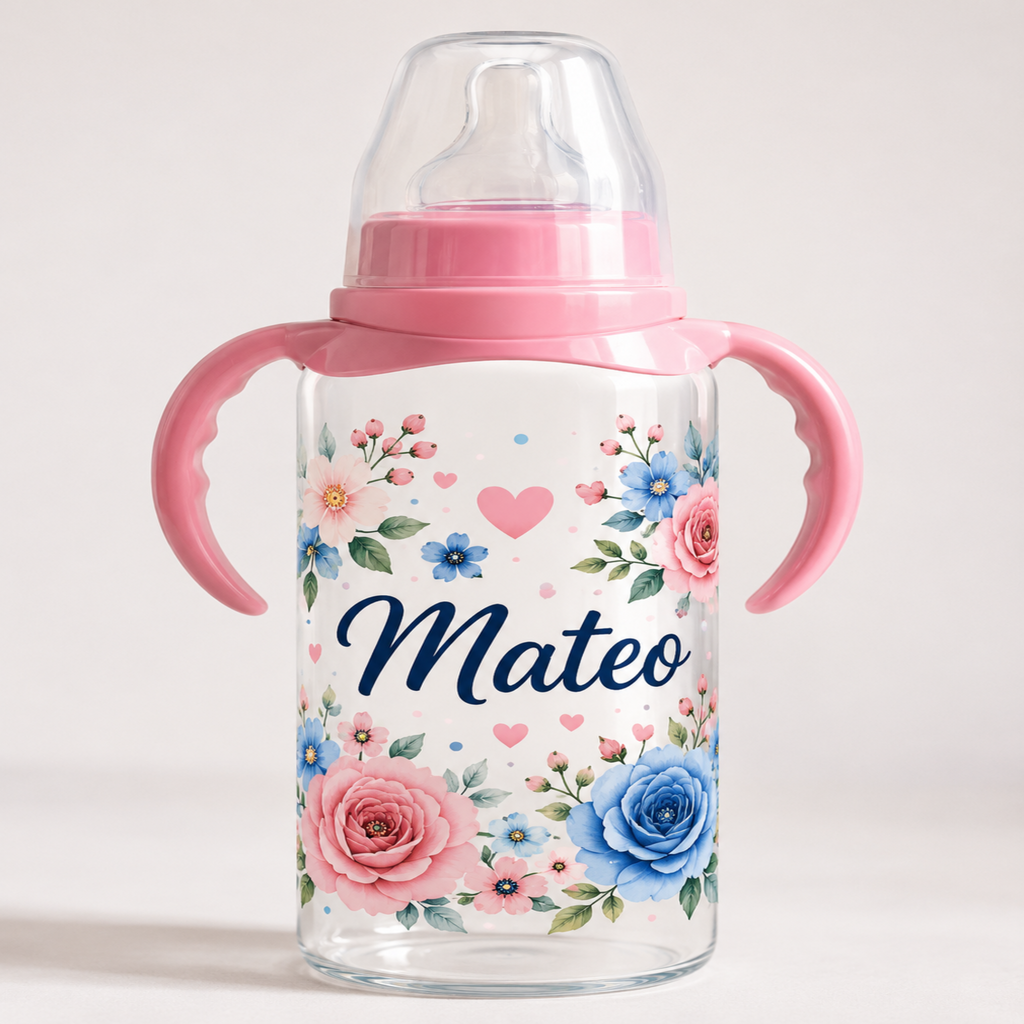 A clear baby bottle with pink handles and a pink collar, decorated with a watercolor floral pattern in pink, blue, and green, and personalized with the name 'Mateo' in navy script. The bottle is shown on a clean, light beige background.