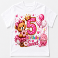 A white short-sleeve kids' t-shirt featuring a colorful '5 Birthday Sweet' graphic print with a teddy bear, cupcakes, balloons, and stars.