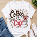A white graphic t-shirt featuring the Spanish phrase 'Coffee First Café Primero El Cafe' in brown and pink lettering with a coffee cup illustration, styled in a flat-lay with blue jeans, white sneakers, and a small plant on a light wood background.