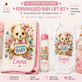 Personalized teddy bear baby gift set featuring a pink plush blanket, a white baby bodysuit, and a baby bottle, all printed with a cute cartoon teddy bear holding a 'Welcome Baby' sign surrounded by pink and blue flowers. The names 'Emma' and 'Emily' are printed on the blanket and bottle.