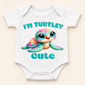 White short-sleeve baby bodysuit with a colorful cartoon turtle graphic and the text 'I'M TURTLEY Cute' printed on the front, shown on a light beige background.