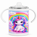 A white handled baby tumbler with a clear lid, featuring a colorful cartoon unicorn illustration with a rainbow, clouds, and stars on the front.